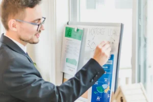Businessman in suit writing mortgage loan rates on whiteboard during a real estate meeting