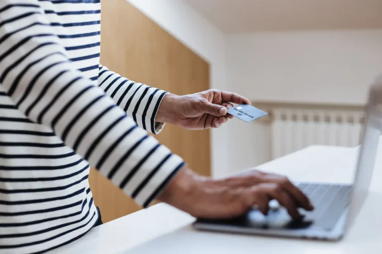 Person using a credit card for online shopping on a laptop at home