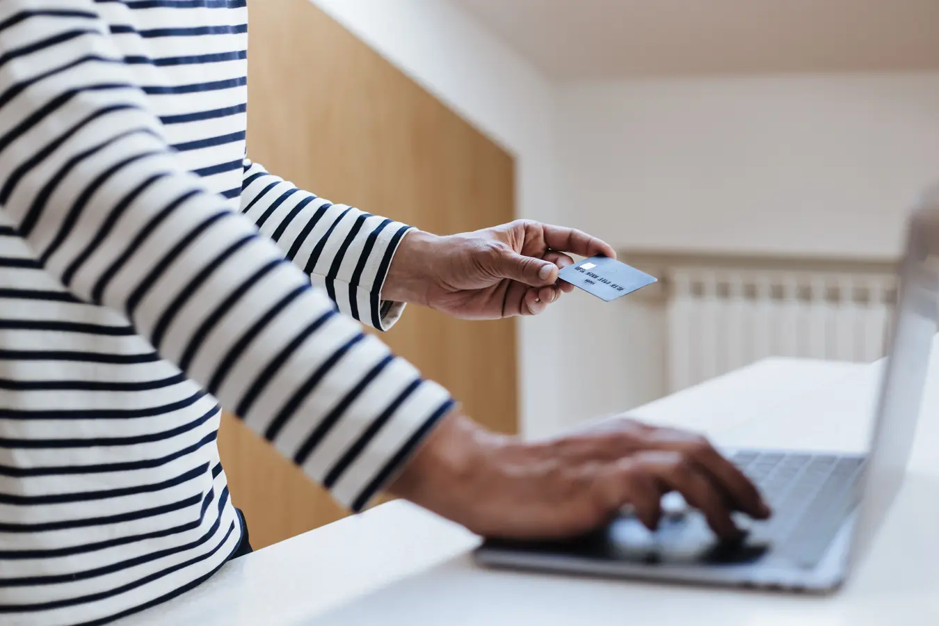 Person using a credit card for online shopping on a laptop at home