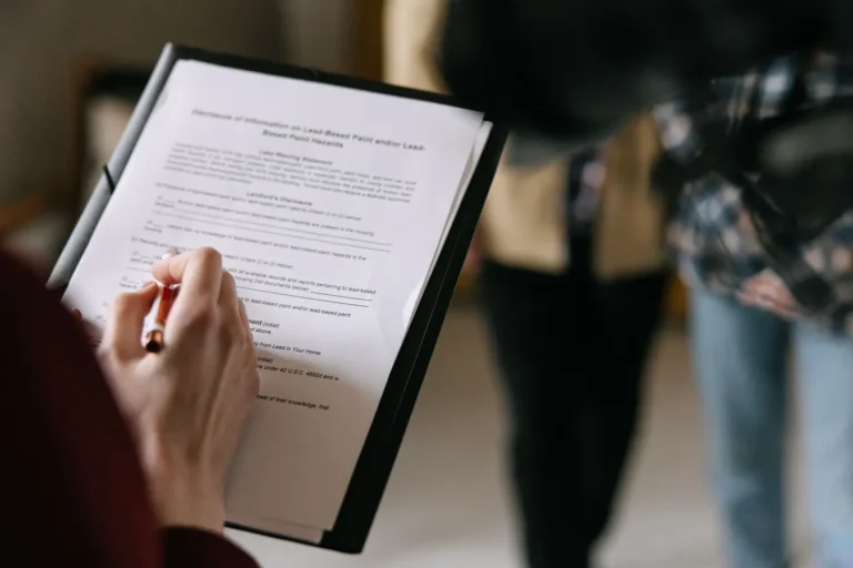 Couple reviewing real estate documents indoors while writing and discussing mortgage details