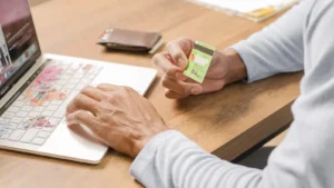 Person holding a credit card while shopping online on a laptop in India