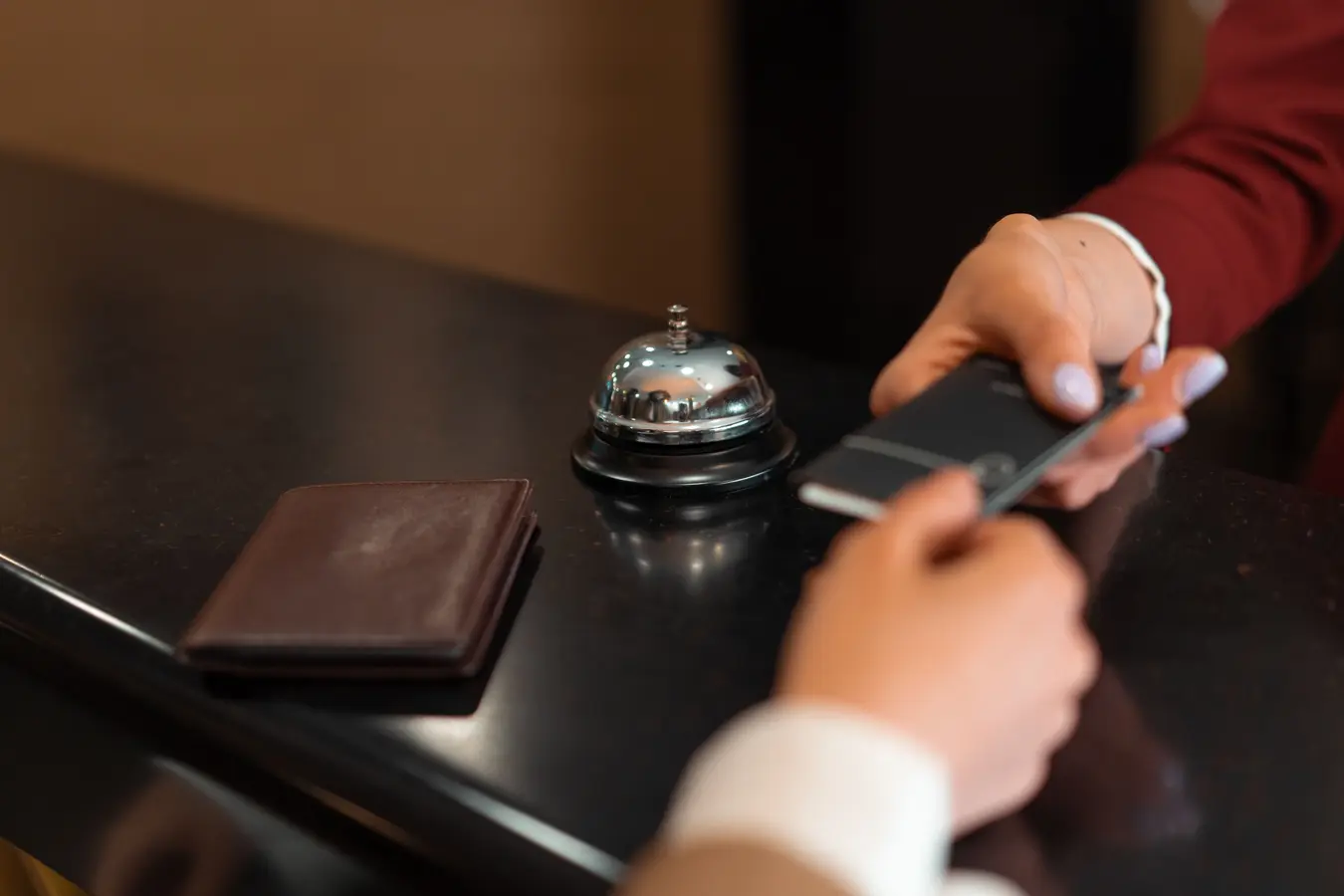 Close-up of hotel check-in with smartphone and credit card payment at the reception desk