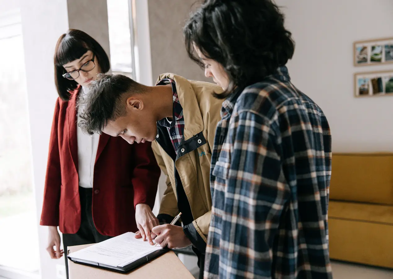 Young couple signing mortgage loan paperwork with a real estate agent indoors