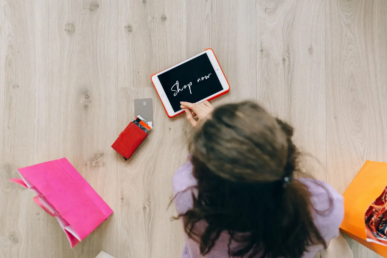 Woman using a tablet for online shopping with bags and cards nearby