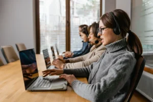 Customer service team using laptops and headsets in a modern office, relevant to Vtiger CRM software