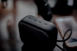 Sleek waterproof Bluetooth portable speaker beside a smartphone on a wooden table