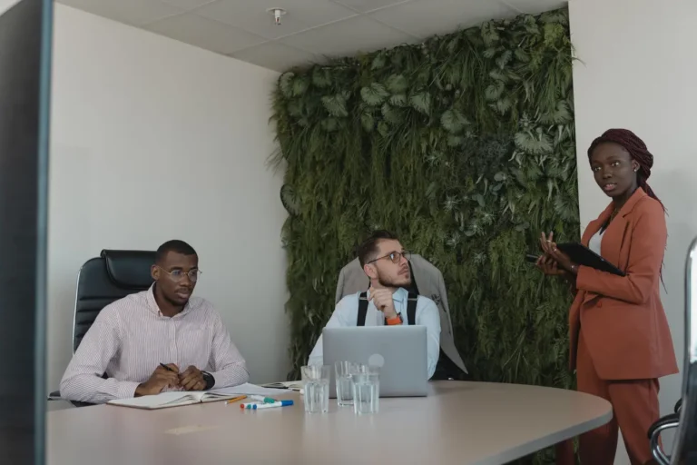 Professionals in a strategic office meeting with green plants, reflecting discussions on when ESG investing started