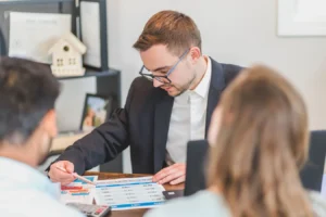 Real estate agent explaining wrap-around mortgage meaning to clients in an office
